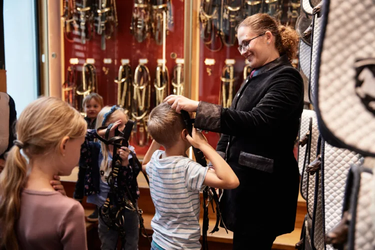 Frau zeigt Kindern Zaumzeug, lachend