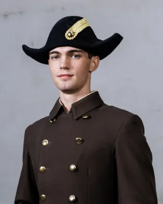 junger Mann in brauner Uniform mit Zweispitz schaut in die Kamera, Bereiteranwärter der Spanischen Hofreitschule