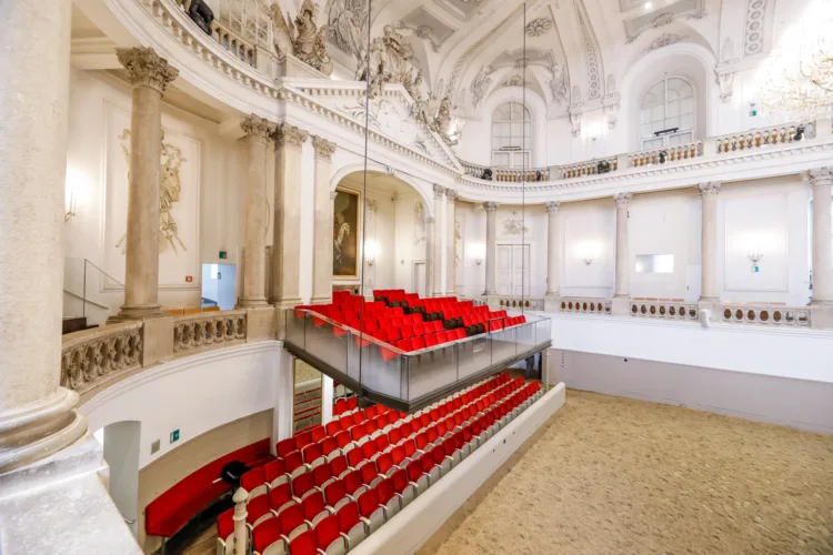 barocke Reithalle, in der man zwei logen mit roten Sitzplätzen sieht.
