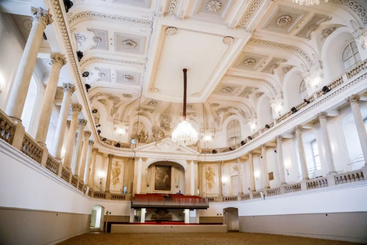 Reine barocke Reithalle mit Säulen und einer reich verzierten Decke mit einem Kristallluster