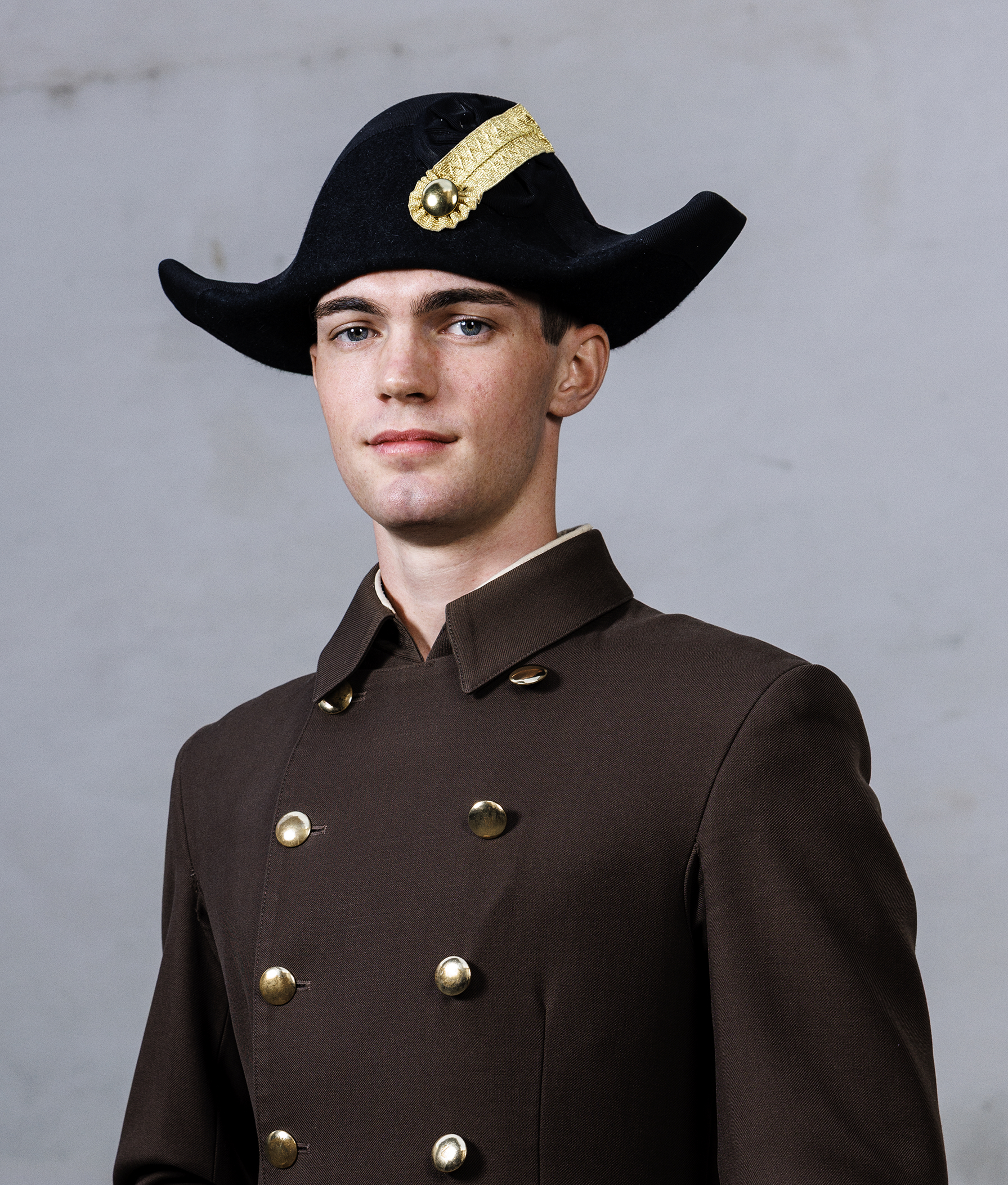 junger Mann in brauner Uniform mit Zweispitz schaut in die Kamera, Bereiteranwärter der Spanischen Hofreitschule